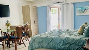 Ein Schlafzimmer mit einem Bett, einem Glastisch, einem Esstisch mit Stühlen und einem Deckenventilator.