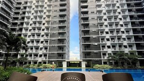 Un moderno edificio de gran altura con múltiples balcones y una zona de piscina.