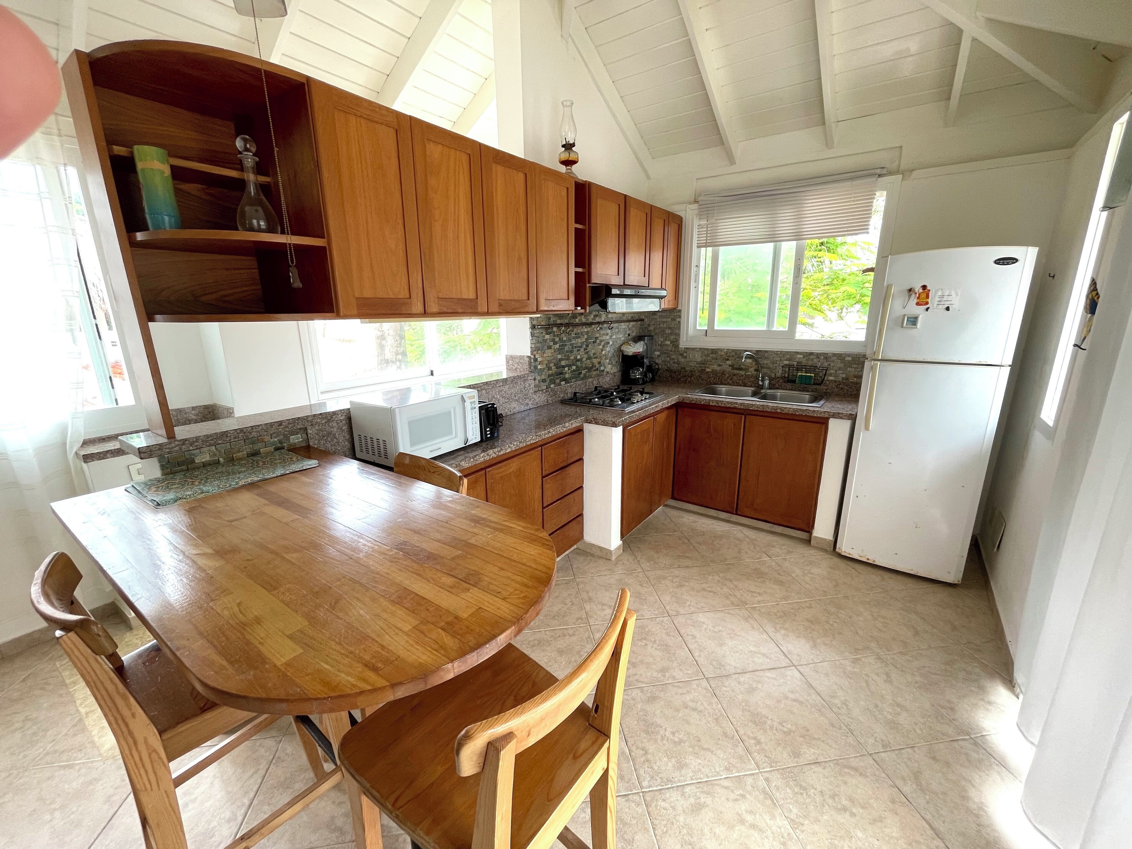 Una cocina con armarios de madera, microondas, estufa y refrigerador.