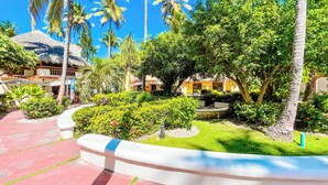 A resort with a tropical garden, palm trees, and a thatched-roof building. - CASAS DEL MAR HOTEL Beach & SPA (Punta Cana)