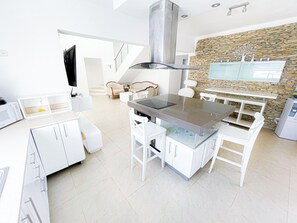 Una cocina moderna con armarios blancos, una isla central y una pared decorativa de piedra.