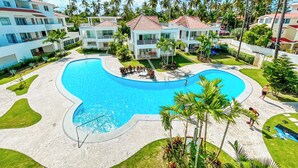 A resort with a large swimming pool, multiple buildings, and palm trees. - CASAS DEL MAR HOTEL Beach & SPA (Punta Cana)