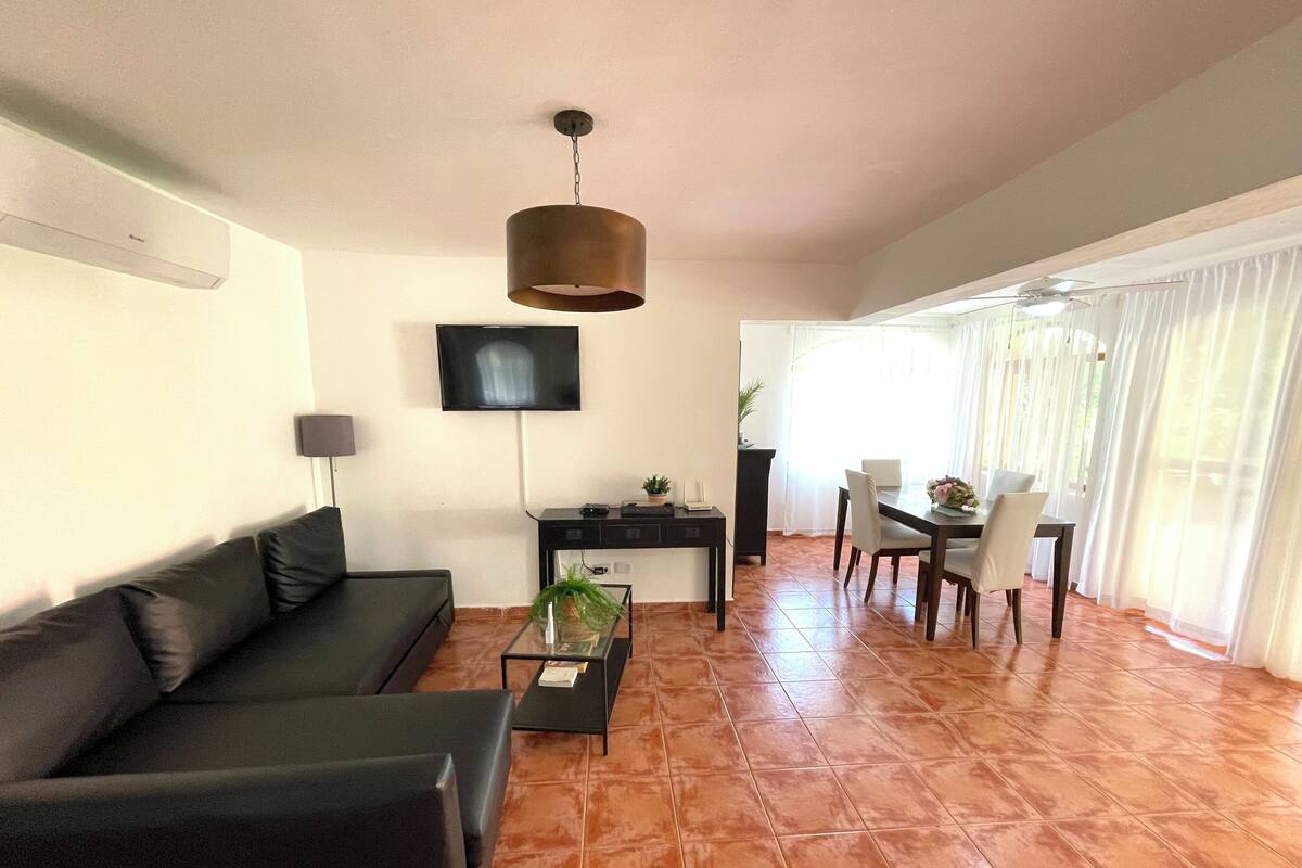 Un salon comprenant un canapé, une table basse, un téléviseur et un coin repas avec une table et des chaises.