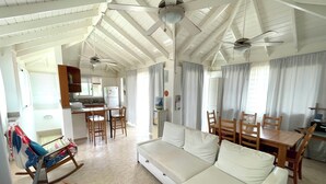 A spacious living area with a white sofa, wooden dining table, and ceiling fans. - CASAS DEL MAR HOTEL Beach & SPA (Punta Cana)