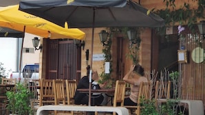 Outdoor seating with umbrellas, a sign for 'Esquina Mineira Restaurante', and wooden chairs.