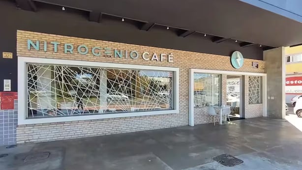 A cafe named NITROGENOCAFE with a modern design, featuring large windows and a visible outdoor seating area.