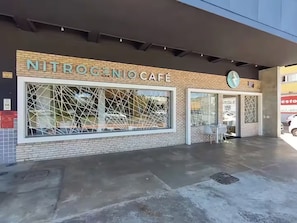A cafe named NITROGENOCAFE with a modern design, featuring large windows and a visible outdoor seating area.