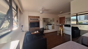 A modern apartment with a living area, kitchenette, and a large window with a view.