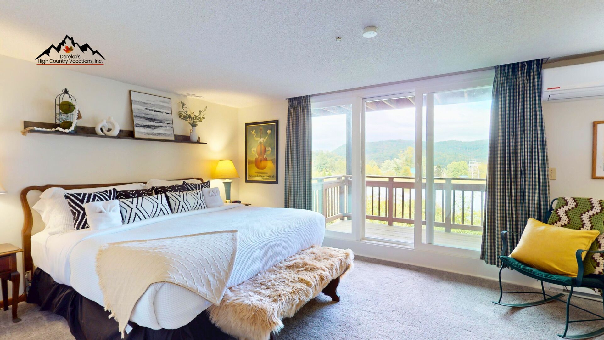 A hotel room with a large bed, a bench, a rocking chair, a balcony with curtains, and a view of the outdoors.
