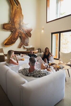 A modern living room with a large wooden sculpture, a white sofa, and a glass coffee table.
