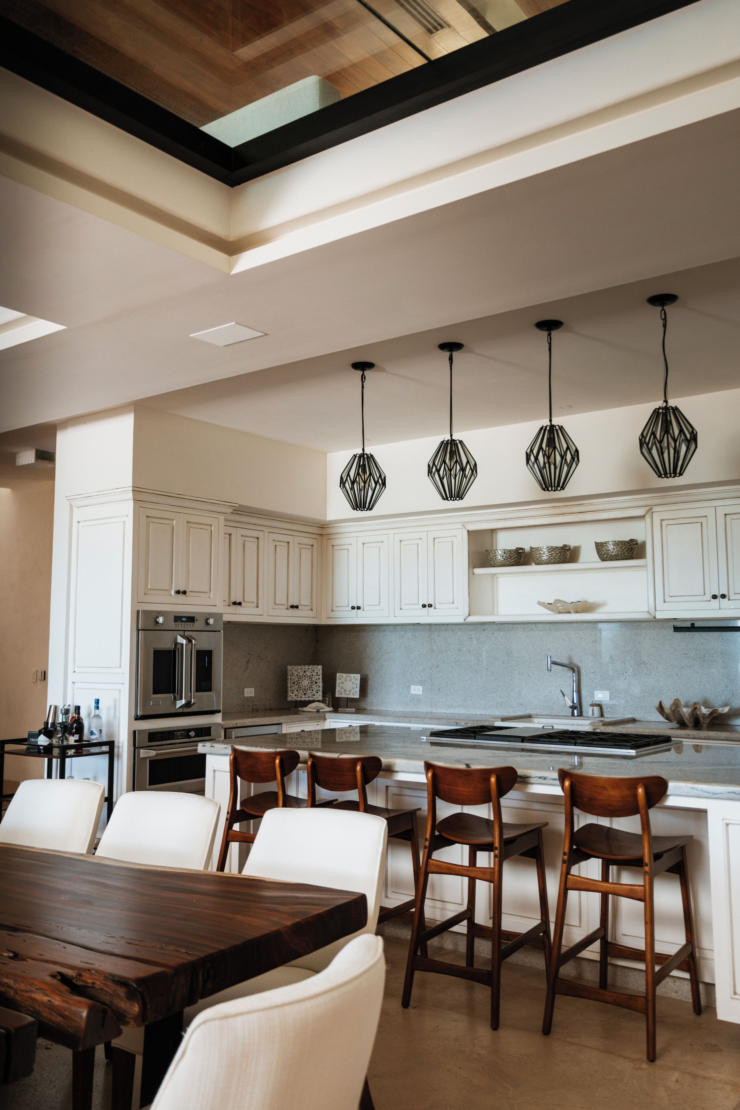 A modern kitchen with white cabinetry, a central island, and pendant lighting.