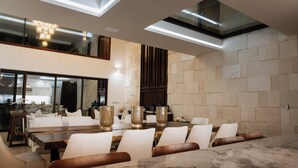 Un espace repas moderne avec une table en marbre, des chaises blanches et de grands vases.