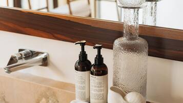 A bathroom vanity with a wooden tray holding toiletries, a large mirror, and a towel rack in the background.