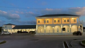 A large building with multiple arches and a flat roof, surrounded by parked cars. - Town Center Abaco (Marsh Harbour)