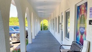 A covered corridor with benches, a security camera, and a mural on the wall. - Town Center Abaco (Marsh Harbour)