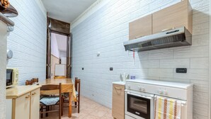 Eine kleine Küche mit Holztisch, Stühlen, einem weißen Backofen und einer eingebauten Mikrowelle.