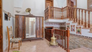 Ein geräumiger Wohnbereich mit einer Holztreppe, einem Schrank, einem Sessel und einem dekorativen Messingobjekt.