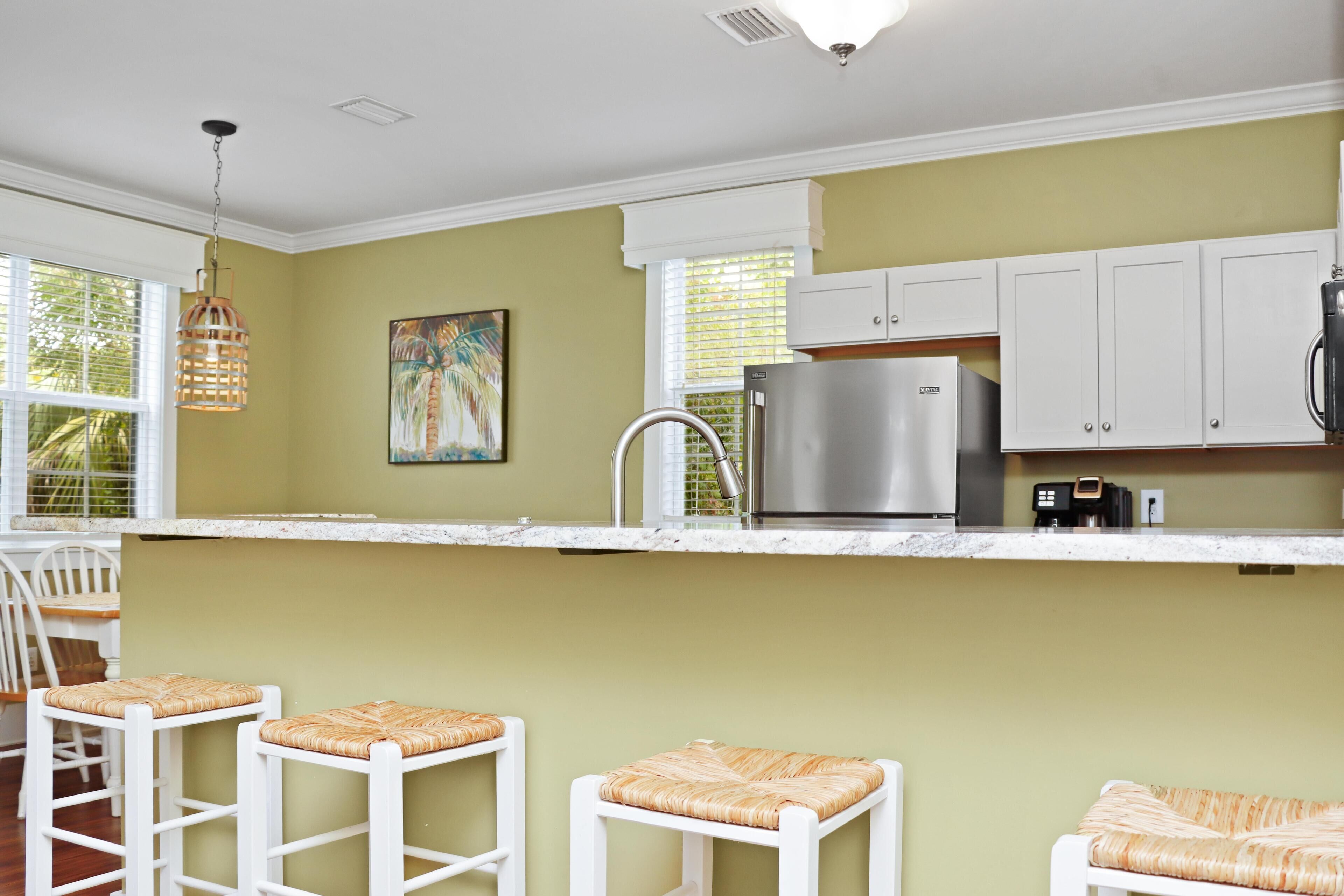 A kitchen with white cabinets, a stainless steel refrigerator, and a hanging light fixture.