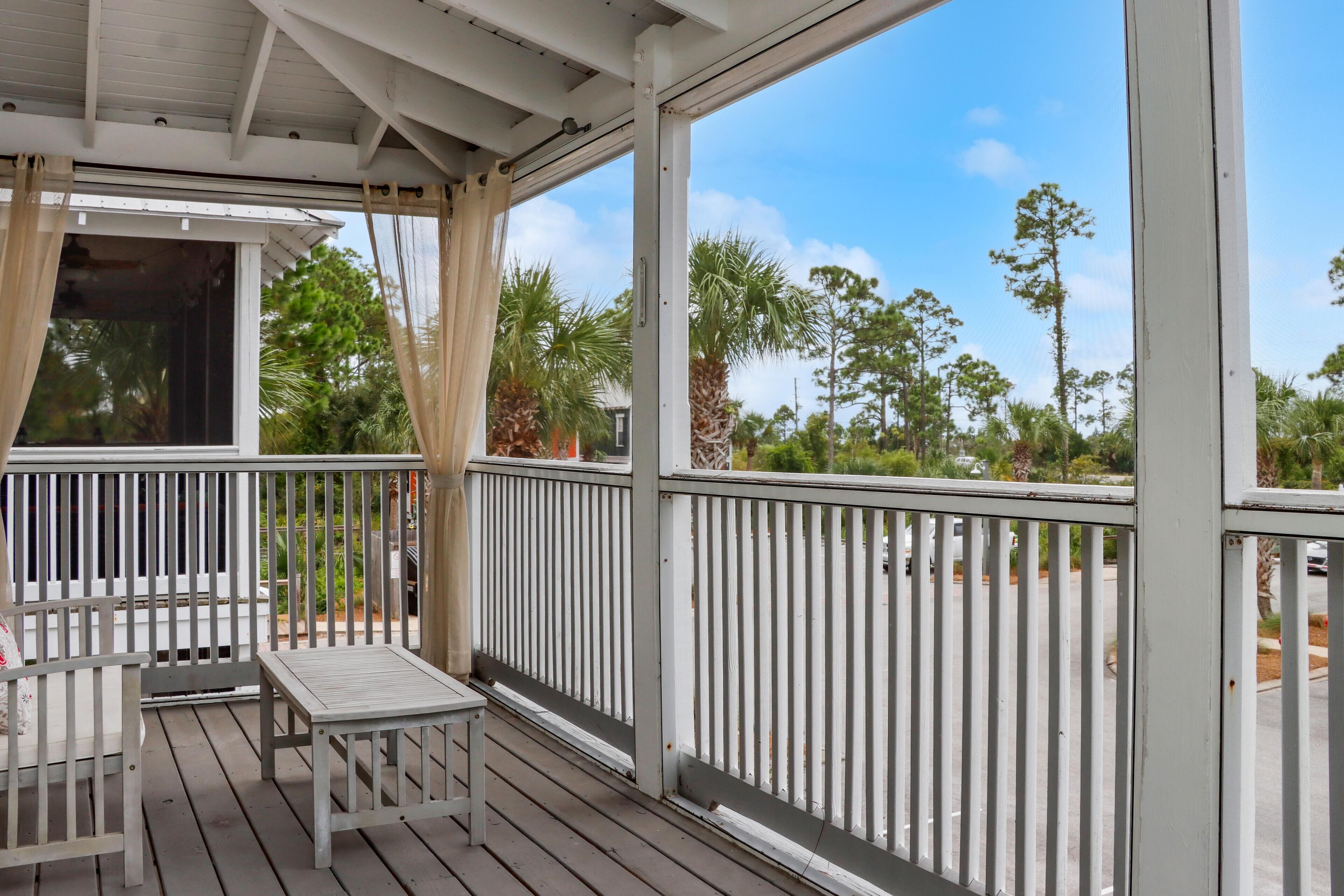 A covered outdoor area with a wooden deck, white railings, and a table.