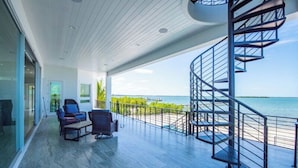 Een modern interieur met een spiraaltrap die leidt naar een balkon met uitzicht op zee.