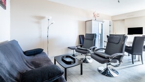 A modern living room with a sofa, two armchairs, a coffee table, and a ceiling fan. - 3-Star Tourist Apartment with Sea View, Wi-Fi, and Air Conditioning (Golfe-Juan)