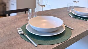 A dining table with two plates, two wine glasses, and cutlery.