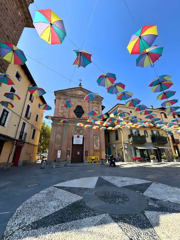 A street with colorful umbrellas, a building with a central door, and a tiled pavement.