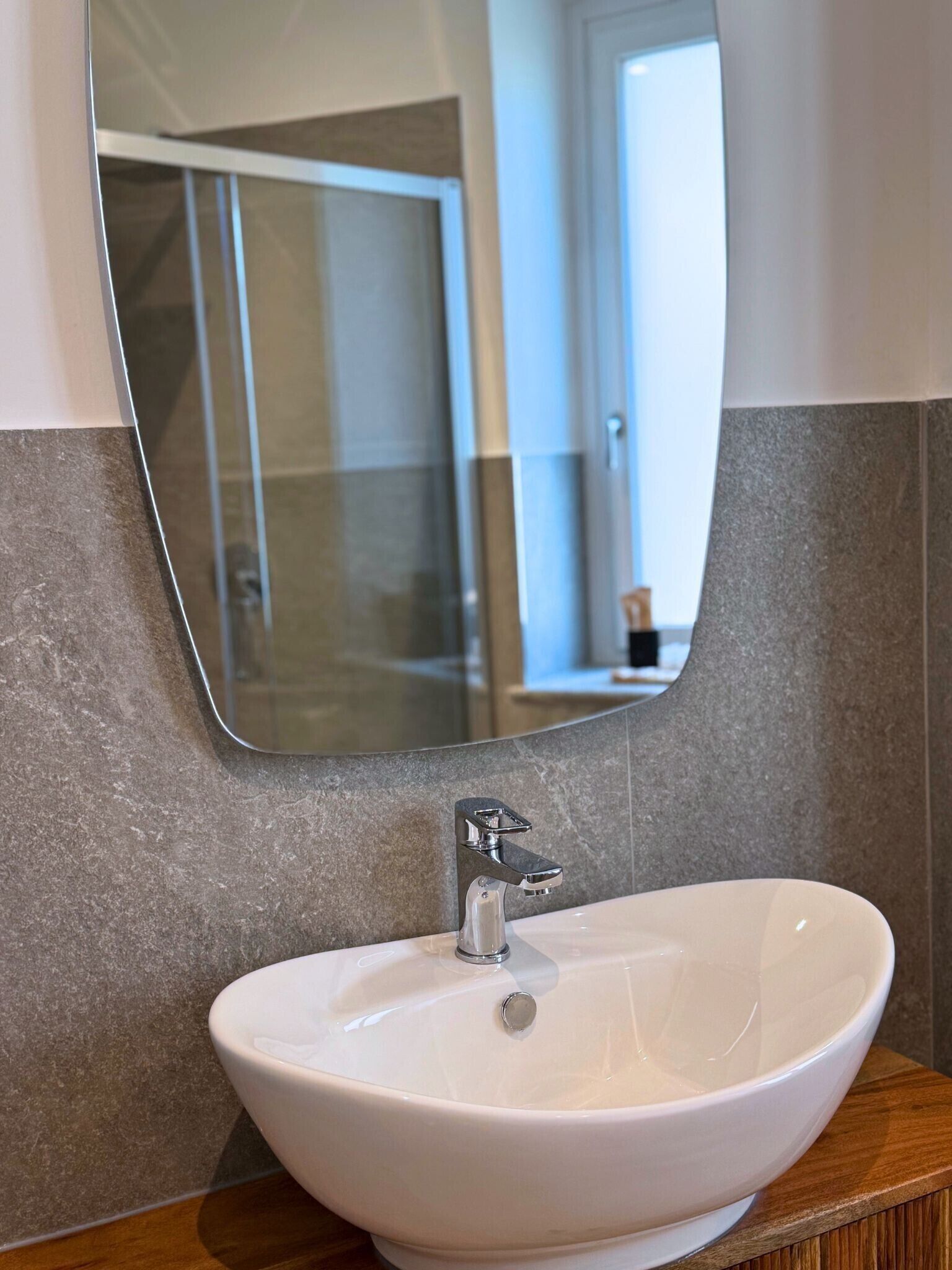 Une salle de bain avec un lavabo blanc, un miroir et un espace douche.