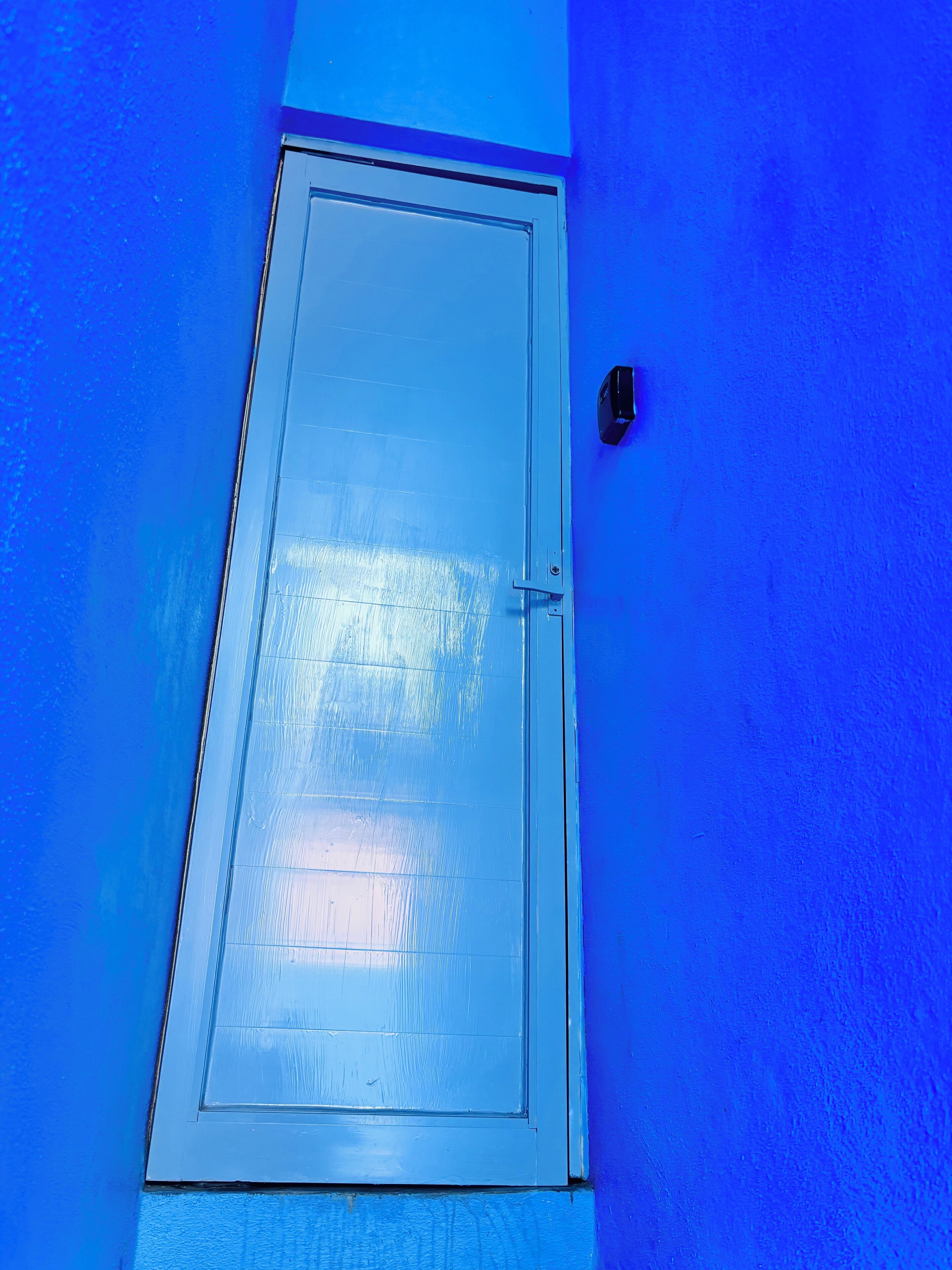 A door with a handle and a lock on a blue wall.