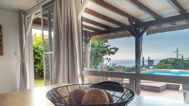 Ein Zimmer mit Meerblick, einem Pool und einem Tisch mit Obstschale.