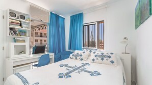 Une chambre à coucher avec un lit, un bureau, une chaise, une bibliothèque et une fenêtre avec des rideaux.