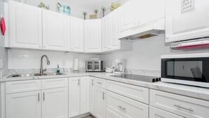 A kitchen with white cabinets, a microwave, a toaster, and a sink. - Unit 126 Beautiful Cedar key (Cedar Key)
