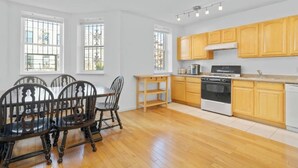 Une cuisine moderne avec des meubles en bois, une cuisinière et un coin repas comprenant une table et des chaises.