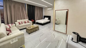 A modern hotel room with a sofa, a bed, a coffee table, and a large mirror. - Jerash Hotel (Jerash)