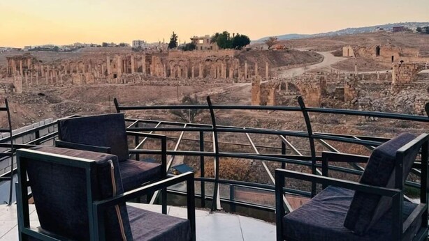 A terrace with chairs overlooking ancient ruins. - Jerash Hotel (Jerash)