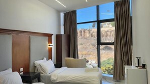 A hotel room with two beds, a TV, a desk, and a view of ancient ruins. - Jerash Hotel (Jerash)
