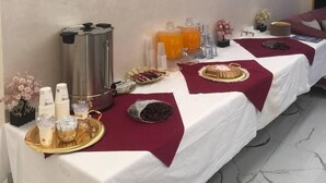 A long dining table with a white tablecloth, covered with red placemats, and various food items and drinks. - Jerash Hotel (Jerash)