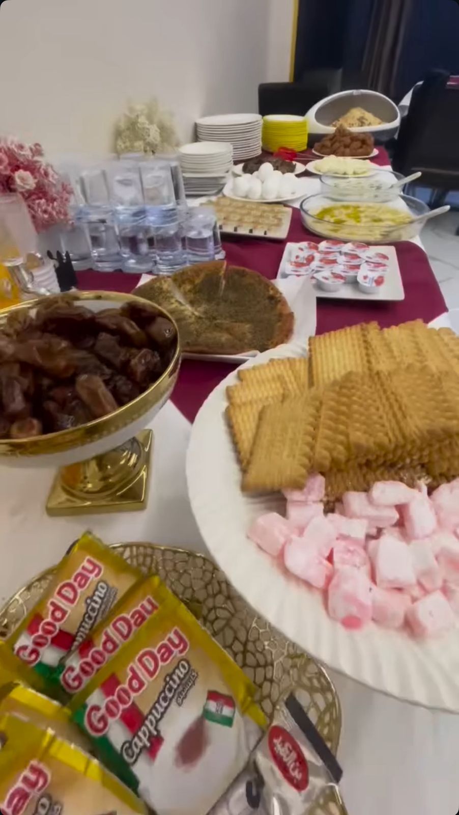 Un tavolo da buffet con diversi cibi, tra cui un'ampia ciotola di carne, piatti di cracker e confezioni di Good Day Cappuccino.