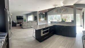 Una cocina moderna con armarios oscuros, encimeras de granito y un horno empotrado.