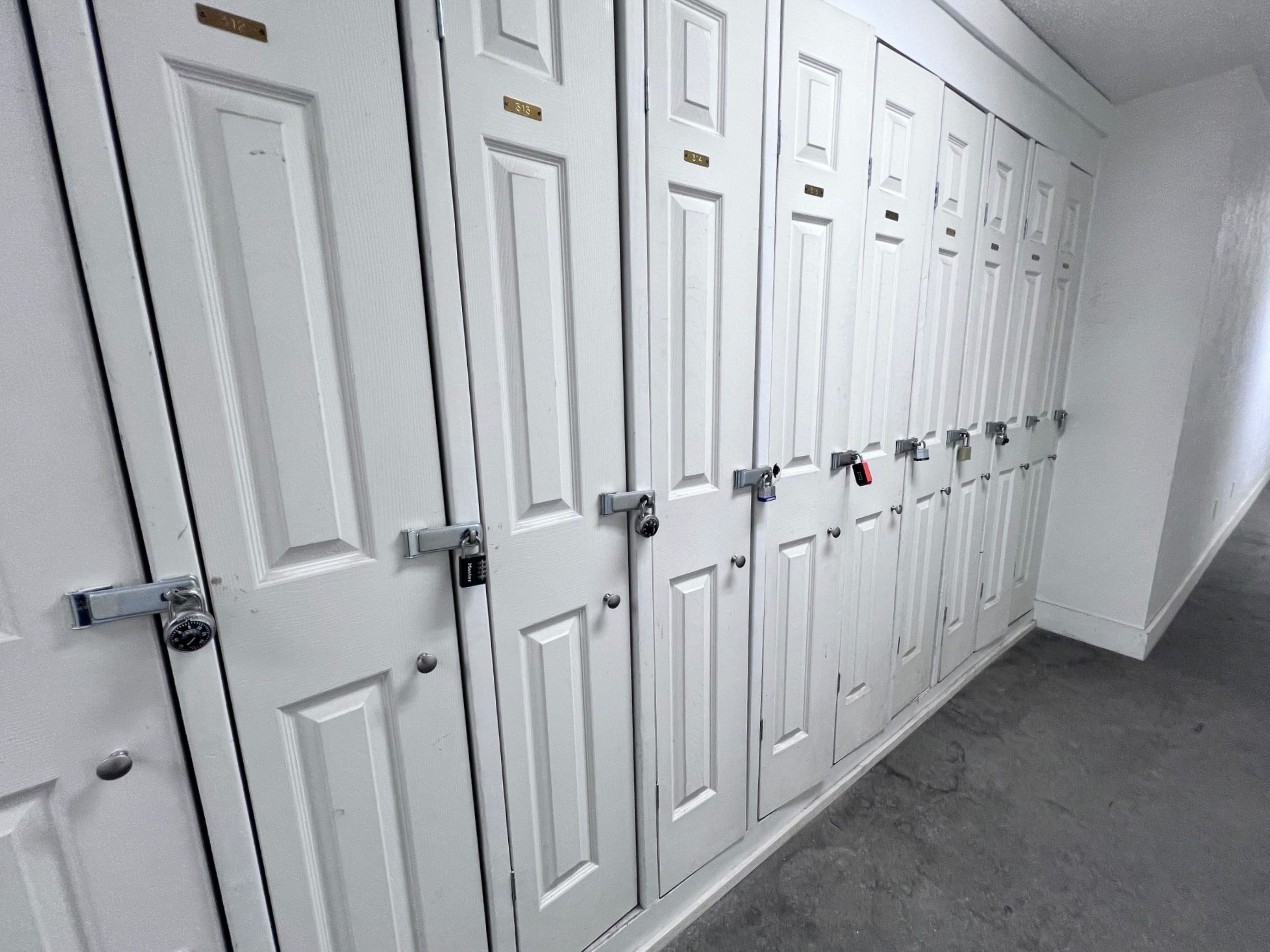 A row of white doors with numbered locks, indicating a secure storage area.