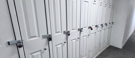A row of white doors with numbered locks, indicating a secure storage area.