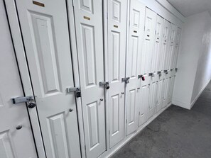 A row of white doors with numbered locks, indicating a secure storage area.