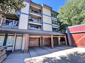 A multi-story building with a covered parking area and a red garage door. - Longbranch • 30+ day rental near Main St, Breck Slopes  and Trails (Breckenridge)
