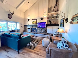 A cozy living room with a fireplace, comfortable seating, and decorative antlers on the wall.