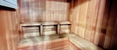A sauna with wooden benches and a sloped floor.