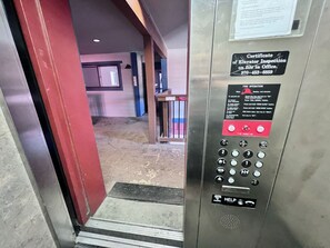 An elevator interior with a fire operation panel, a certificate of elevator inspection, and a help button. - Longbranch • 30+ day rental near Main St, Breck Slopes  and Trails (Breckenridge)