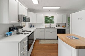 A modern kitchen with white cabinetry, a built-in oven, a stove, and a sink. - Waterfront Views, Kayaks, Pets w/ Fee (Creal Springs)