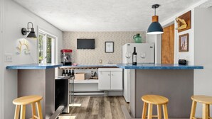 A compact kitchen with a blue countertop, wooden stools, and a patterned backsplash. - Wild Sun Retreat- Waterfront, firepit, Kayak, lily pad, pet friendly with fee (Creal Springs)