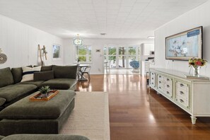 A modern living room with a sectional sofa, a dining area, and a kitchen with white cabinetry. - Waterfront Views, Kayaks, Pets w/ Fee (Creal Springs)