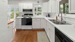 A modern kitchen with white cabinetry, a stainless steel sink, and a built-in oven. - Wild Sun Retreat- Waterfront, firepit, Kayak, lily pad, pet friendly with fee (Creal Springs)